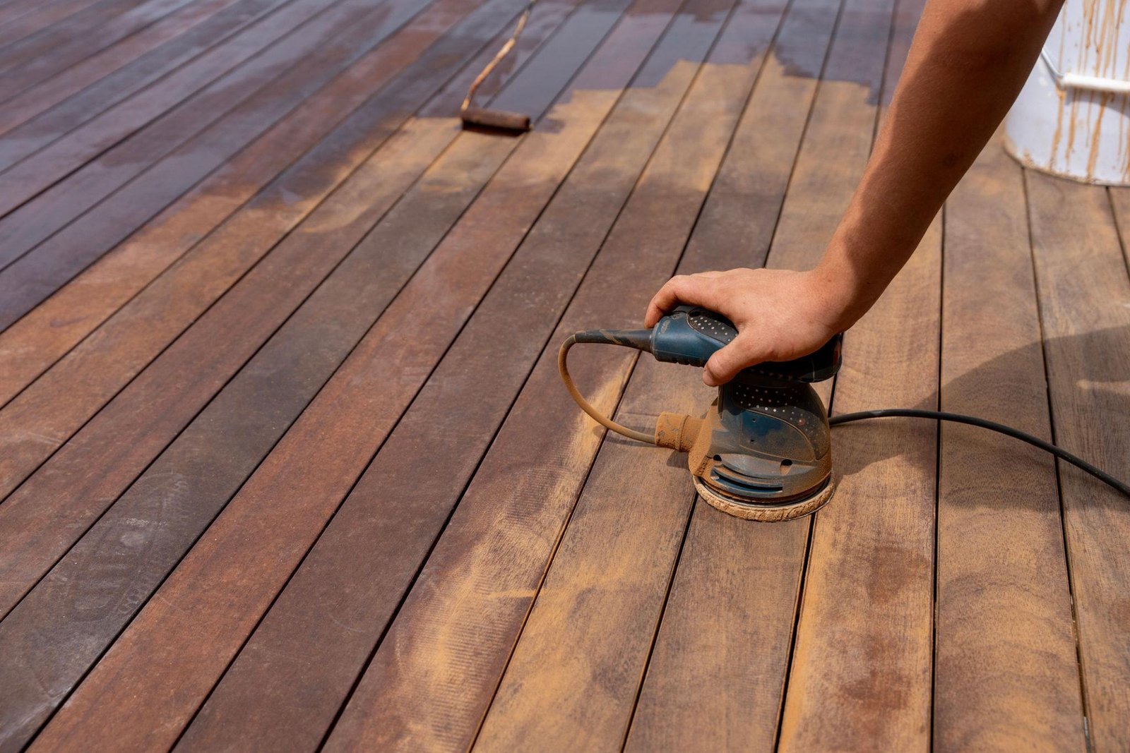 Professional Fence and Deck Staining and sanding on a wooden outdoor surface.