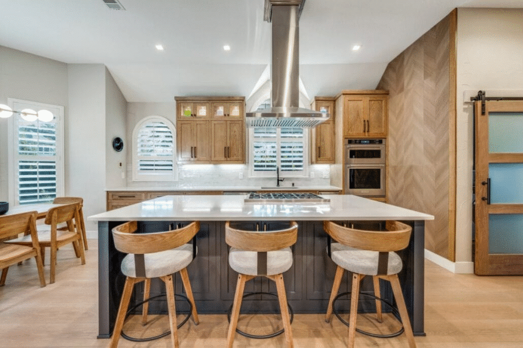 Modern kitchen with island, wooden cabinets, bar stools and stylish lighting